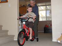28-Poppy_helps_Kenny_ride_his_bike_in_the_house