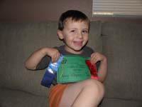 16-excited_Kenny_with_his_graduation_certificate_and_swim_meet_ribbons