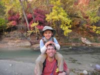 65-Kenny_on_Daddy's_shoulders_by_river_with_fall_colors_at_Temple_of_Sinawava