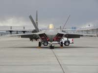 09-F-22_with_Las_Vegas_Strip_in_background-further_beyond_snow_in_west_valley_and_Red_Rock
