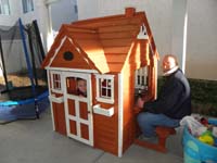 03-Kenny_plays_in_his_playhouse_while_Grandpa_Duke_enjoys_a_beer_at_the_window-tight_squeeze_for_him