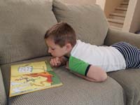 75-Kenny_reads_a_book_on_the_couch-Mommy_makes_Kenny_read_a_book_or_two_each_day,then_logs_it
