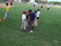 04-baseball_clinic-Daddy_uses_his_hat_to_show_Kenny_how_to_step_on_first_base