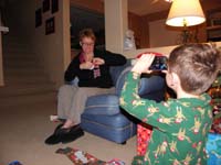 42-Kenny_videos_Mommy_while_she_opens_her_presents_he_picked_out_at_the_Holiday_Bazaar