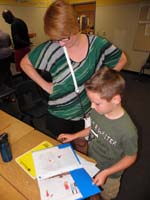 08-showing_Mommy_what_he's_been_working_on_the_past_two_weeks_at_Writing_Camp