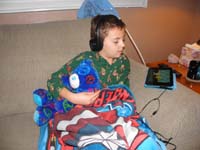 54-Kenny_snuggles_with_'Blueberry'_stuffed_bear_while_watching_video_on_the_Kindle