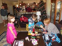 09-unwrapping_presents-Leyna_and_Mommy_watch,Brooke_on_couch-Uncle_Jeff_to_left