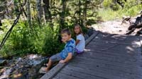 02-Kenny_and_Zoe_relaxing_on_a_bridge_over_a_creek_by_our_campsite