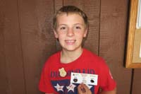 090-Kenny_shows_off_his_badge_and_special_volcanic_rock_he_received_from_ranger-cinder,pumic,obsidian